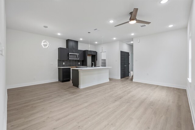 kitchen featuring ceiling fan, light hardwood / wood-style flooring, backsplash, decorative light fixtures, and a kitchen island