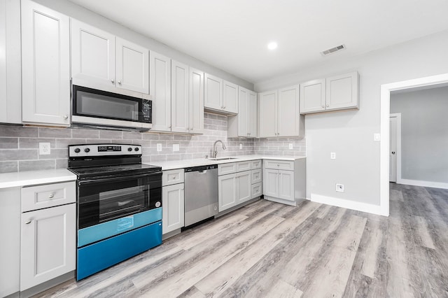 kitchen featuring stainless steel appliances, white cabinetry, sink, tasteful backsplash, and light hardwood / wood-style flooring