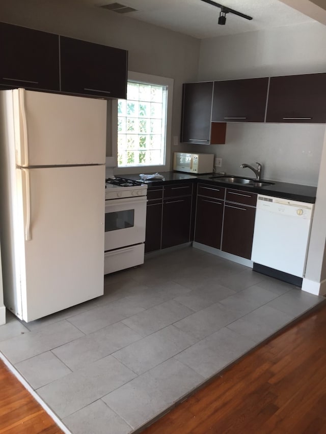 kitchen featuring light wood-type flooring, dark brown cabinetry, sink, and white appliances