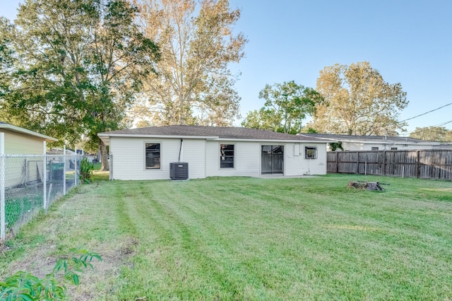 back of house featuring central AC unit and a lawn