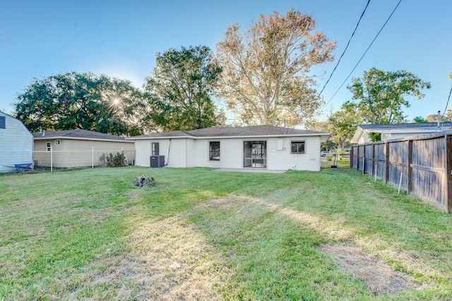 rear view of property featuring cooling unit and a yard