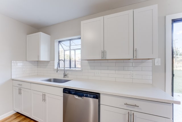 kitchen featuring tasteful backsplash, white cabinetry, sink, dishwasher, and light hardwood / wood-style flooring