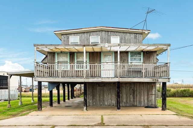 raised beach house with a porch, a carport, and a front yard