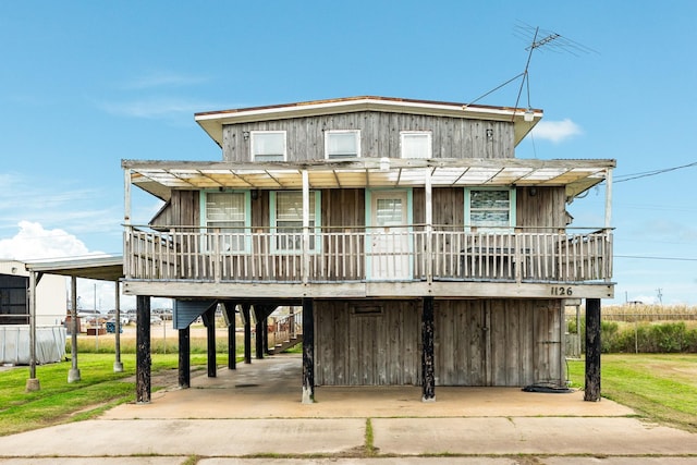 beach home featuring a porch, a front yard, and a carport