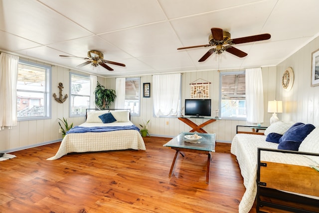 bedroom with ceiling fan, multiple windows, and hardwood / wood-style floors