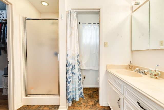 full bath featuring stone finish flooring, a stall shower, vanity, and baseboards