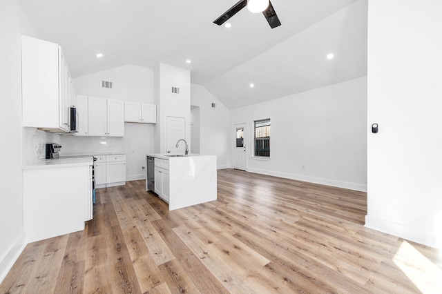 kitchen featuring electric stove, sink, a kitchen island with sink, white cabinetry, and light hardwood / wood-style flooring