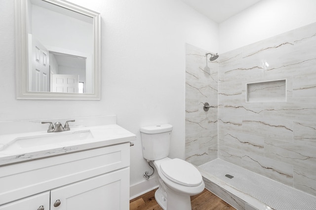 bathroom featuring toilet, hardwood / wood-style floors, vanity, and a tile shower