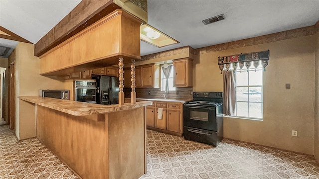 kitchen with kitchen peninsula, vaulted ceiling, plenty of natural light, and black appliances