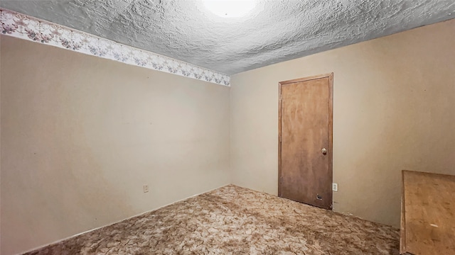 empty room featuring carpet and a textured ceiling