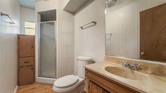 bathroom with toilet, wood walls, an enclosed shower, and wood-type flooring