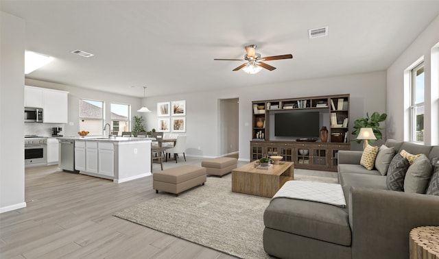 living room featuring light hardwood / wood-style flooring, ceiling fan, and sink