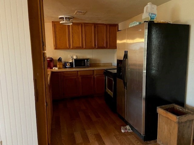 kitchen with stainless steel refrigerator with ice dispenser, dark hardwood / wood-style flooring, and black range with electric stovetop