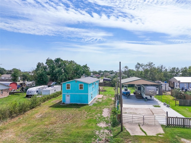 381 Center St, Matagorda, TX 77457 - view of yard featuring concrete driveway, fence, a carport, a residential view, and a gate