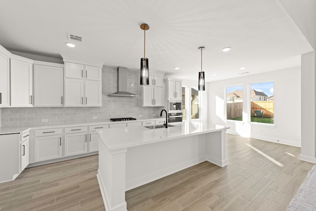 kitchen featuring sink, wall chimney exhaust hood, and white cabinets