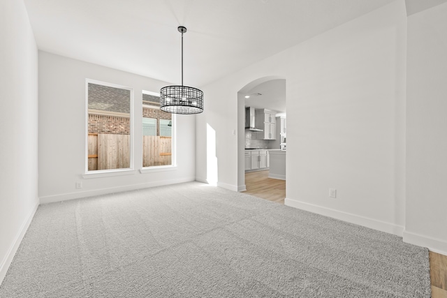 unfurnished dining area featuring a chandelier and light colored carpet