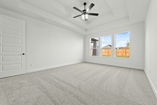 empty room with ceiling fan, a raised ceiling, and carpet