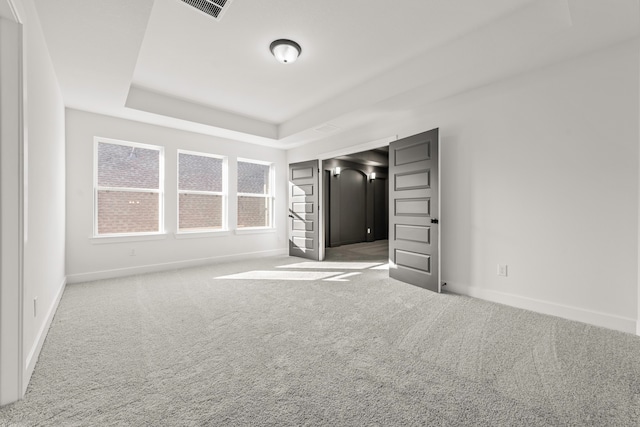 unfurnished bedroom with a raised ceiling and carpet floors