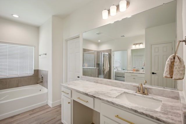 bathroom with hardwood / wood-style floors, vanity, and independent shower and bath