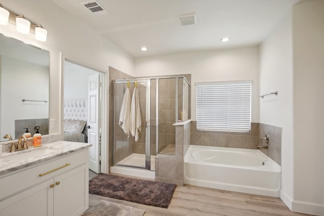 bathroom featuring hardwood / wood-style flooring, vanity, and independent shower and bath