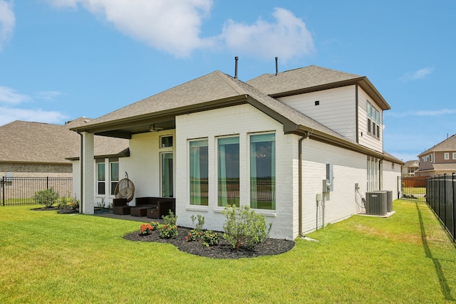 rear view of property featuring central AC unit, ceiling fan, and a lawn