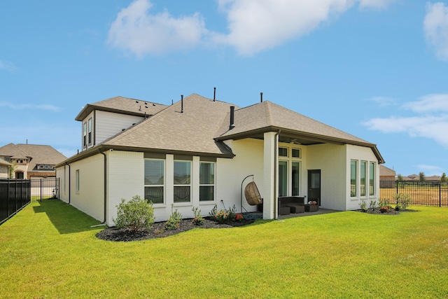 rear view of property featuring ceiling fan and a yard