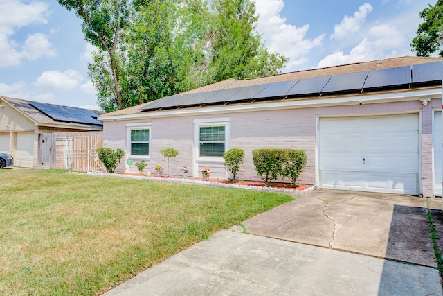 ranch-style home with a front yard, solar panels, and a garage