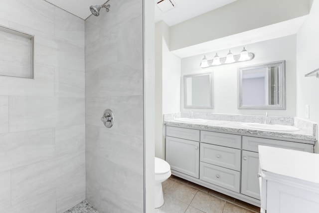 bathroom featuring tiled shower, tile patterned flooring, vanity, and toilet