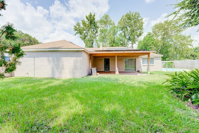 rear view of house featuring a lawn, solar panels, and a patio area