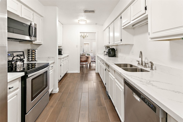 kitchen with sink, appliances with stainless steel finishes, light stone countertops, white cabinets, and dark wood-type flooring