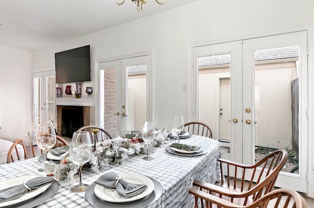 dining room featuring a brick fireplace and french doors