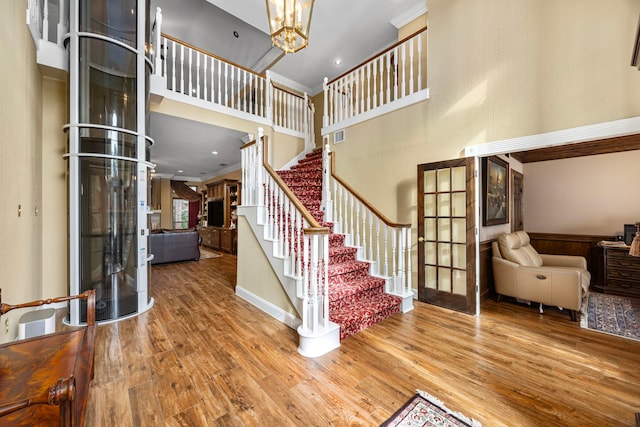 foyer with french doors, ornamental molding, a high ceiling, and hardwood / wood-style flooring