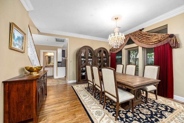 dining area featuring light hardwood / wood-style floors, an inviting chandelier, and crown molding