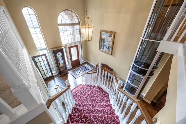 entrance foyer with wood-type flooring, ornate columns, a notable chandelier, and a high ceiling