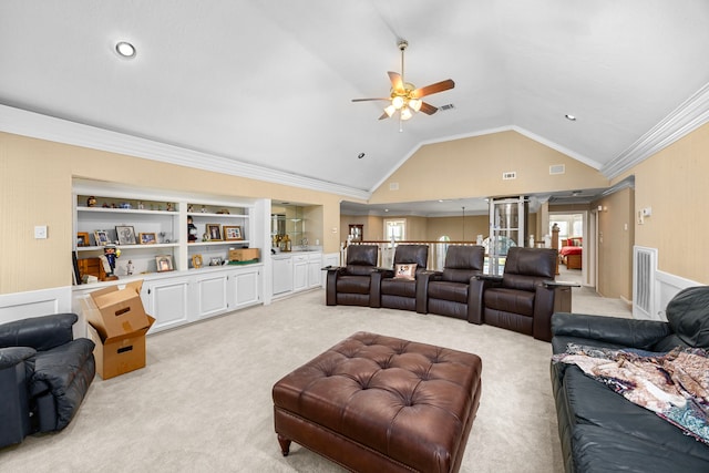 cinema room with built in shelves, crown molding, light colored carpet, and lofted ceiling