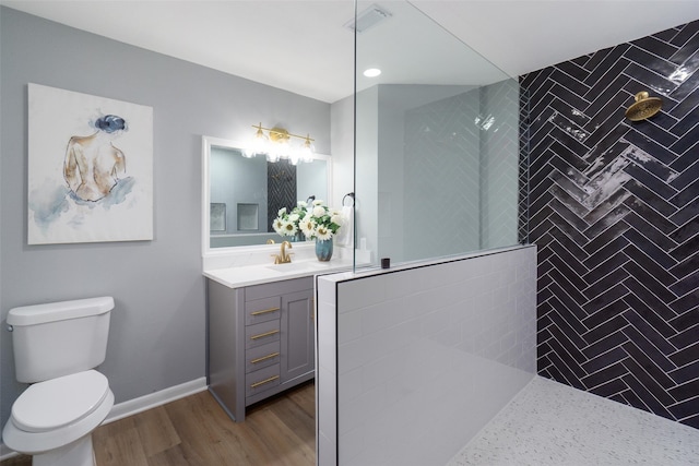 bathroom with tiled shower, hardwood / wood-style flooring, vanity, and toilet