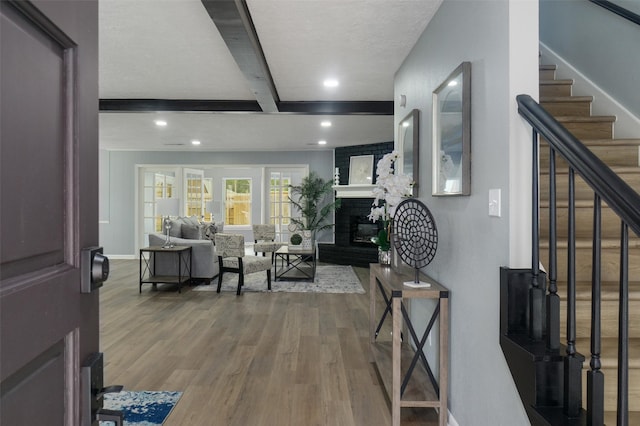 entrance foyer featuring a fireplace, hardwood / wood-style floors, and beamed ceiling