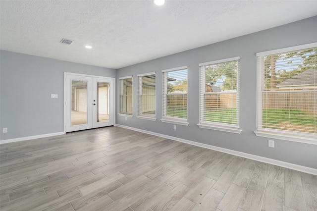 spare room with french doors, a textured ceiling, and light hardwood / wood-style flooring