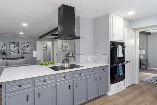 kitchen featuring light hardwood / wood-style flooring, kitchen peninsula, extractor fan, gray cabinets, and black appliances