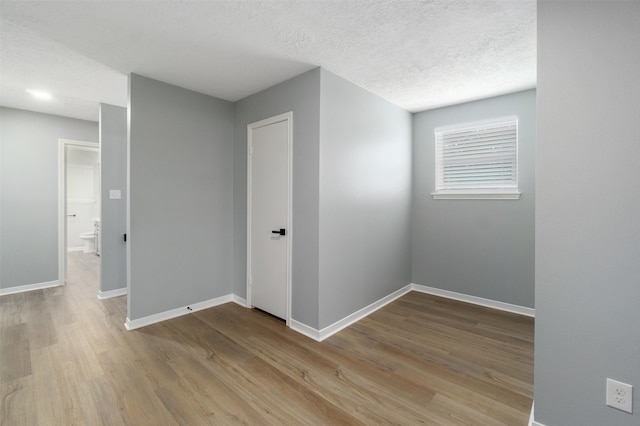 spare room with a textured ceiling and light hardwood / wood-style floors