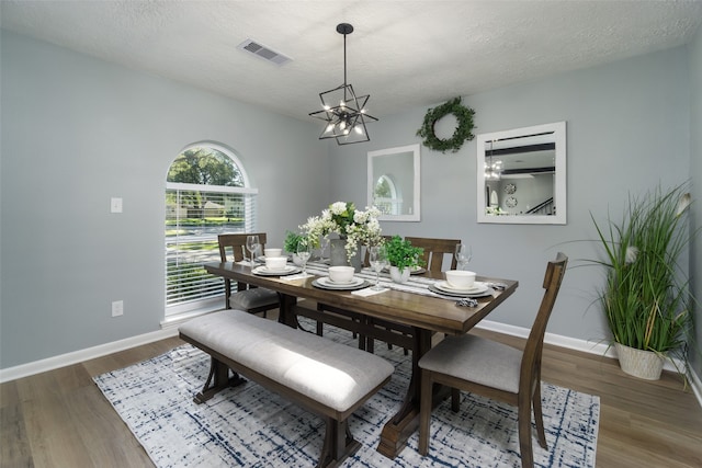 dining room featuring a textured ceiling, hardwood / wood-style flooring, and a notable chandelier