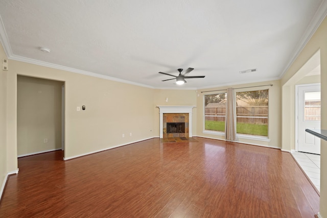 unfurnished living room with a tiled fireplace, hardwood / wood-style flooring, and crown molding