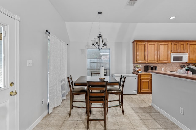 tiled dining area with a chandelier and lofted ceiling