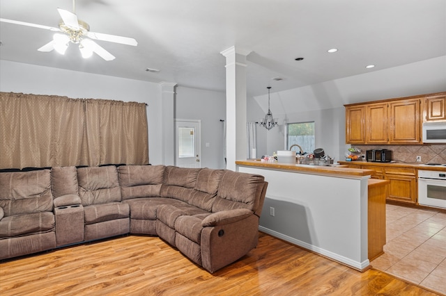 living room with ceiling fan with notable chandelier and light hardwood / wood-style floors