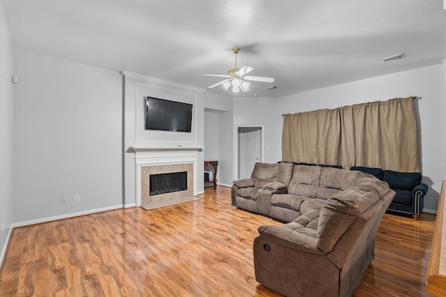 living room with hardwood / wood-style floors, ceiling fan, and a tile fireplace