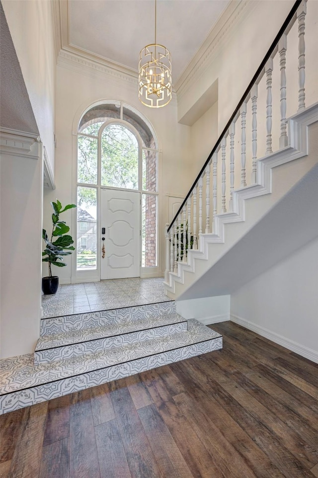 entryway featuring hardwood / wood-style floors, a notable chandelier, a towering ceiling, and crown molding