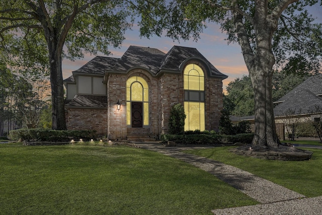 view of front of home with a yard, brick siding, and stucco siding