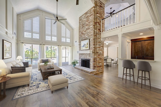 living room featuring a fireplace, a high ceiling, dark hardwood / wood-style flooring, and ceiling fan