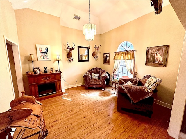 living room featuring hardwood / wood-style flooring, vaulted ceiling, and a notable chandelier