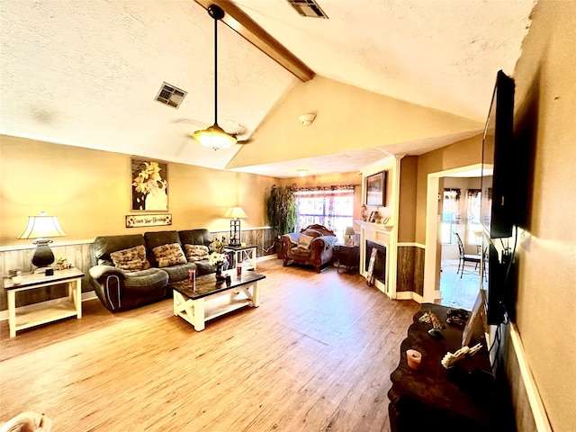 living room with hardwood / wood-style flooring, vaulted ceiling with beams, and a textured ceiling